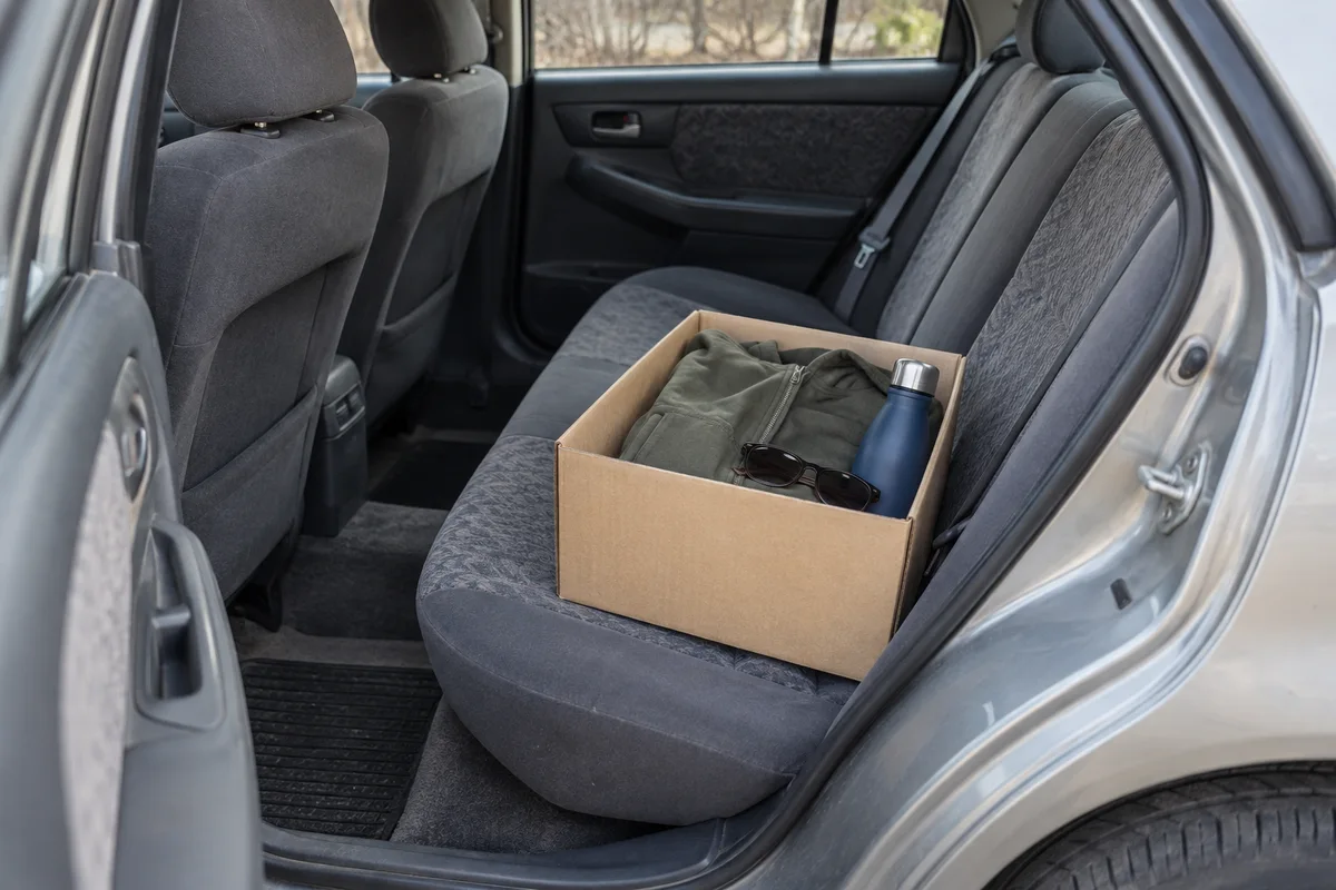 Personal belongings packed in a box on a car’s rear seat.